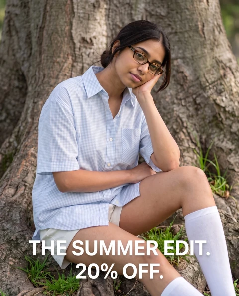 Woman in a pale-blue check shirt seated against a tree. “THE SUMMER EDIT. 20% OFF.”